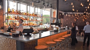 Eine Bar mit Bartender, Barhocker, Flaschenregalen und einer Theke mit Registrierkasse.