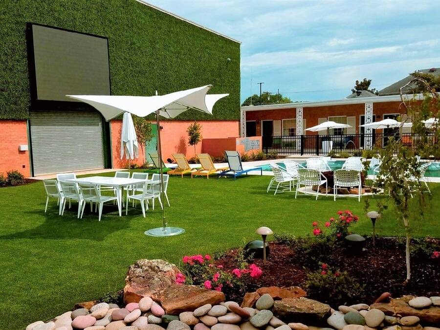 Uma área externa bem cuidada com piscina, espreguiçadeiras e uma mesa de jantar com cadeiras.