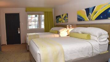 A hotel room with two beds, a window with curtains, and artwork on the wall.