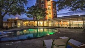 Ein Hotel mit Schwimmbad, Außenbereich und einem Mehrstöckgebäude mit Fenstern.