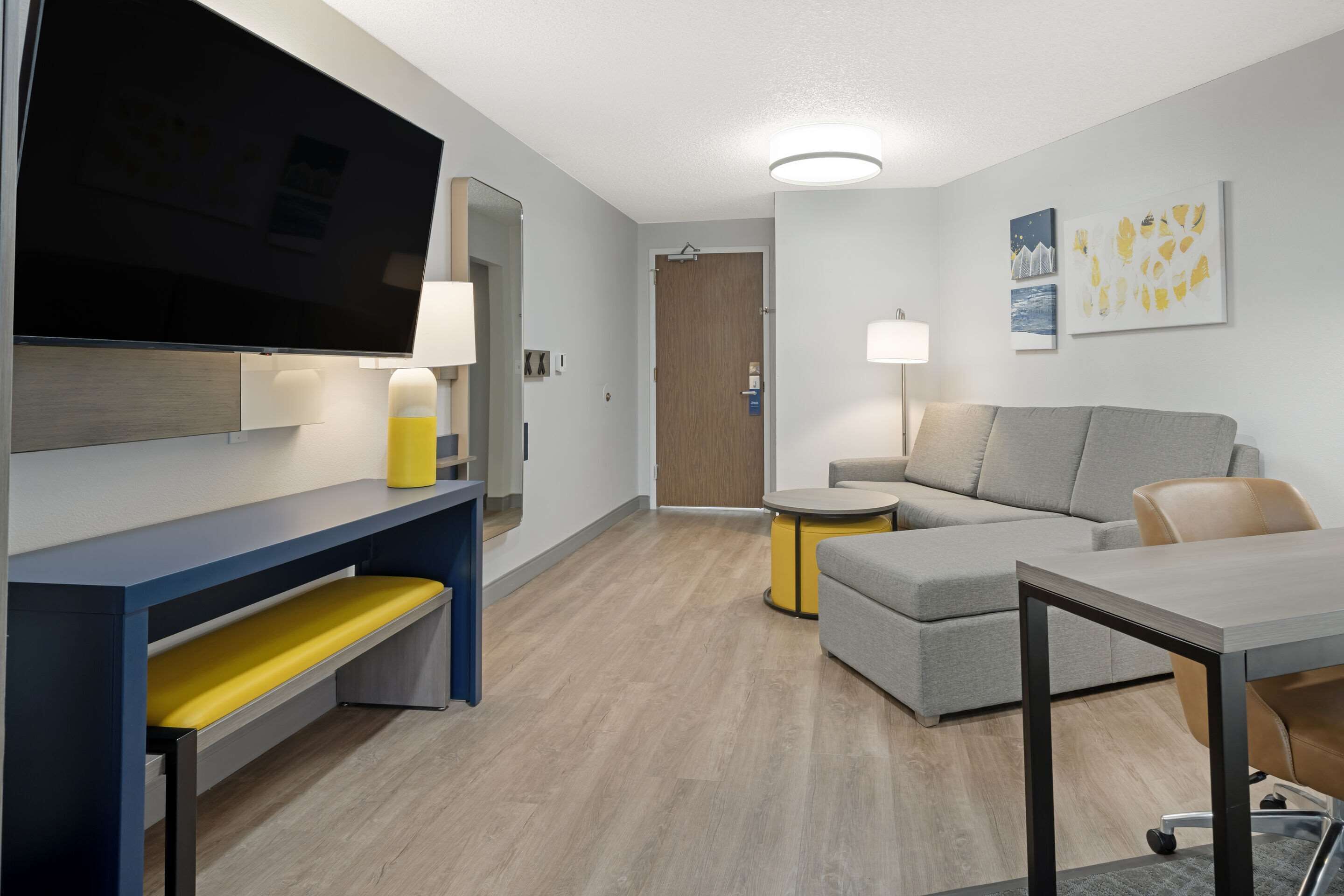 A modern living room with a flat-screen TV, a sofa, a coffee table, and a small side table.