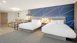 Habitación de hotel con dos camas, un escritorio y una silla. Cuenta con lámparas de pared y una puerta.