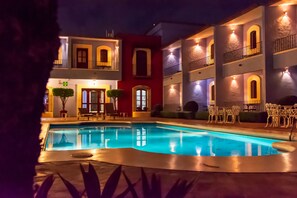 A swimming pool with a view of a building with multiple balconies and outdoor seating. - Hotel Santa Helena Plaza (Oaxaca)