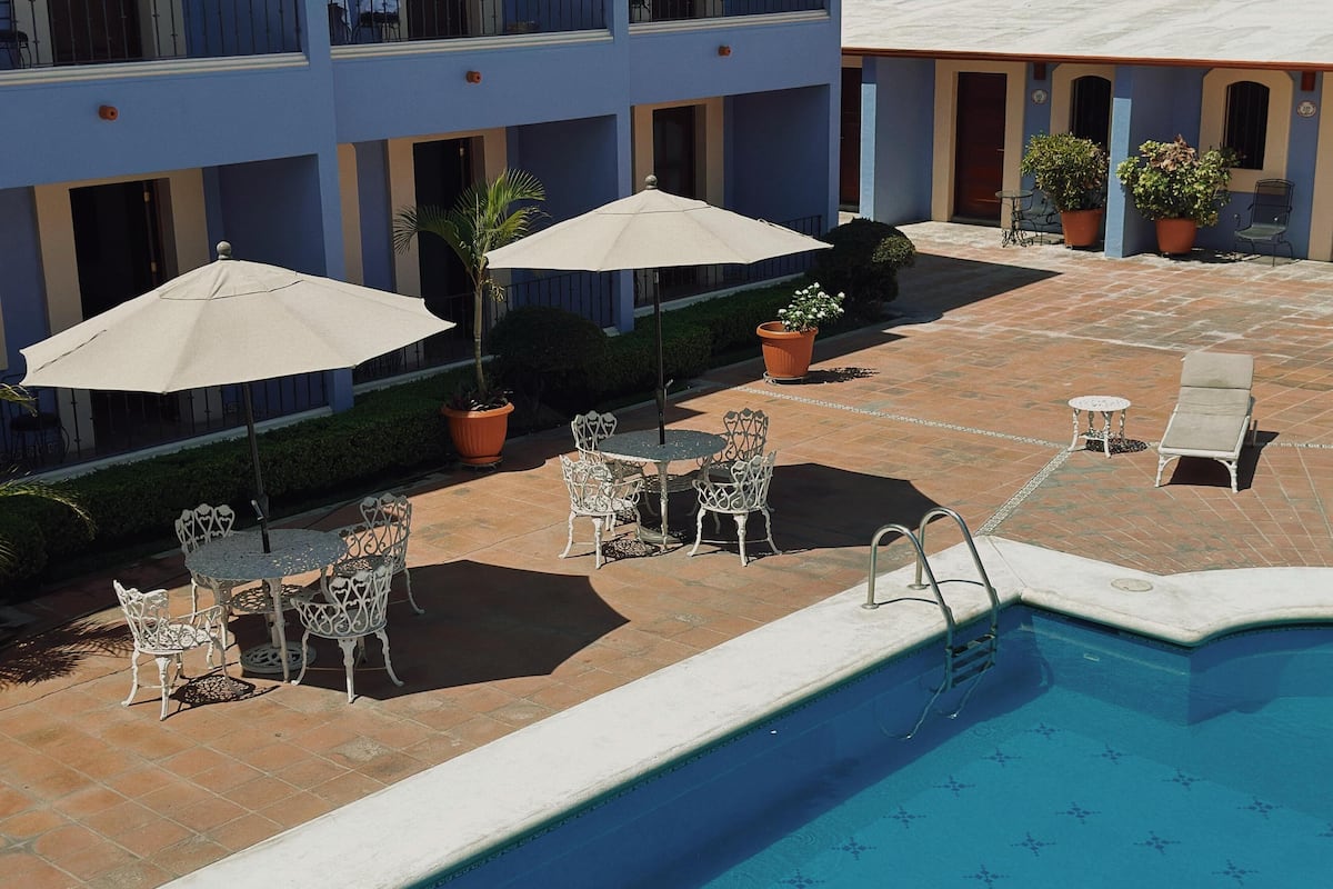 A poolside area with outdoor seating, a pool, and a building with balconies.