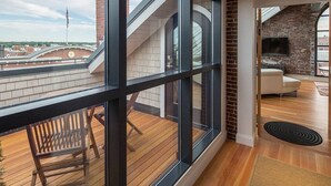 A modern interior with large windows, a wooden deck, and a brick fireplace.