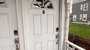 A white door with a 'B' above it, a doormat, and a wooden railing. - Elegant Tacoma condo unit in downtown B (Tacoma)