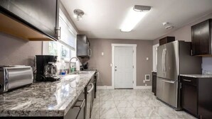 A kitchen with a marble countertop, stainless steel appliances, and a white door. - Elegant Tacoma condo unit in downtown B (Tacoma)