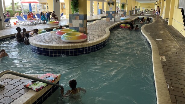 Ein Hallenbad mit mehreren Bahnen, Liegestühlen und einer gefliesten Liegefläche.