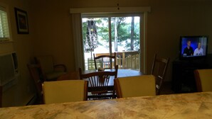 A dining area with a table and chairs, a television, and a view of the outdoors through a sliding door. - Charming Lakefront Retreat: Your Perfect Waterfront Getaway (Lexington)