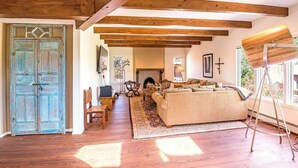A cozy living room with wooden beams, a fireplace, and a large window. - Luxury Home, Perfect Location, Flexible Layout (Santa Fe)