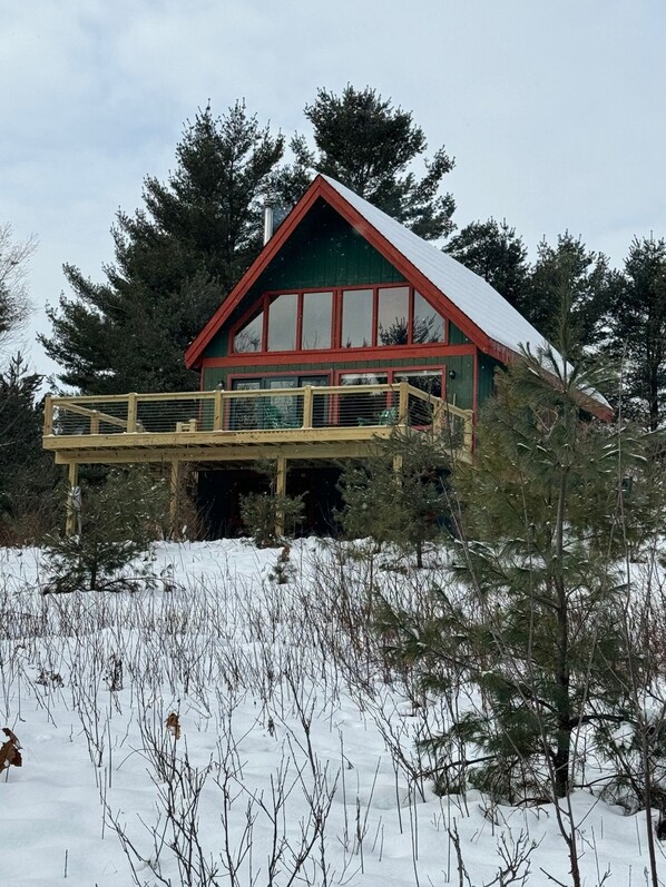 A cabin with a red roof and green walls, surrounded by trees and snow. - Mountain View Chalet (Indian Lake)