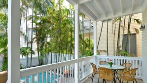 A covered outdoor area with a pool, white railings, and wicker furniture. - 3-Story spacious conch style home w/ private pool & dock! (Key West)