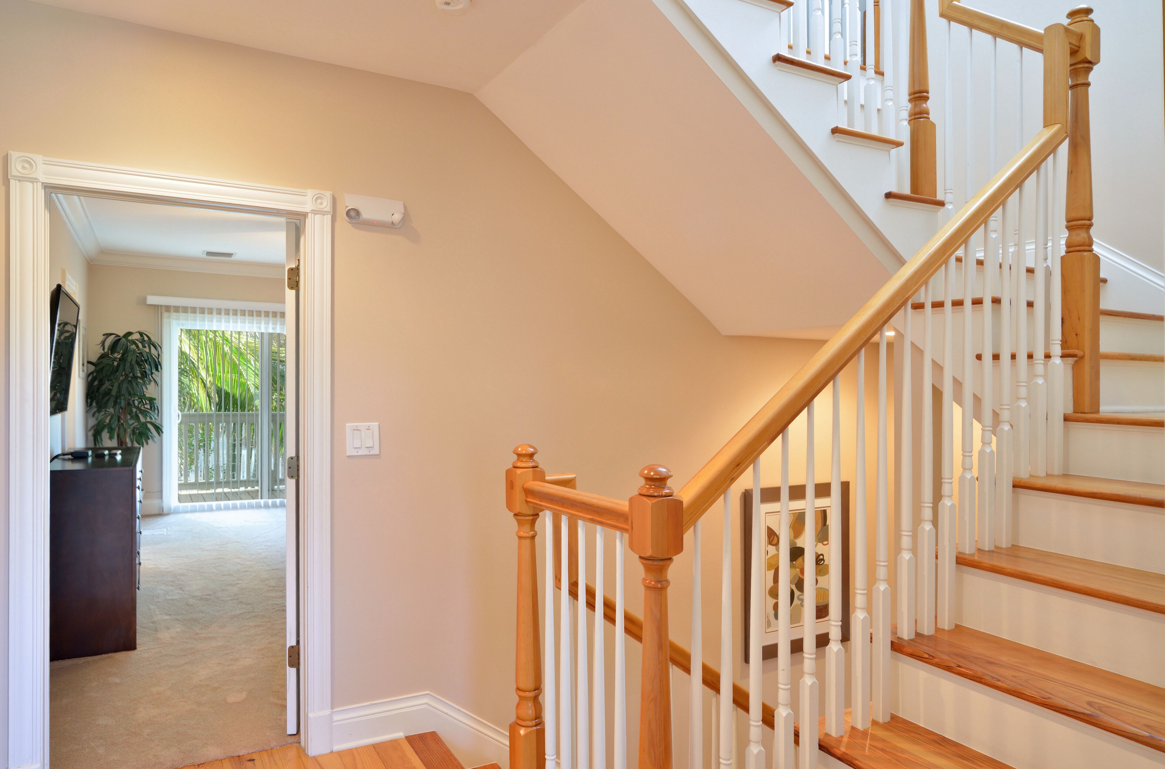A staircase with wooden steps and white balusters, leading to an upper floor.