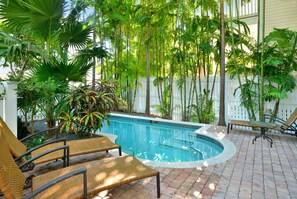 A pool area with a circular pool, lounge chairs, and various tropical plants. - Seafarer's Refuge- ALL FEES INCLUDED (Key West)