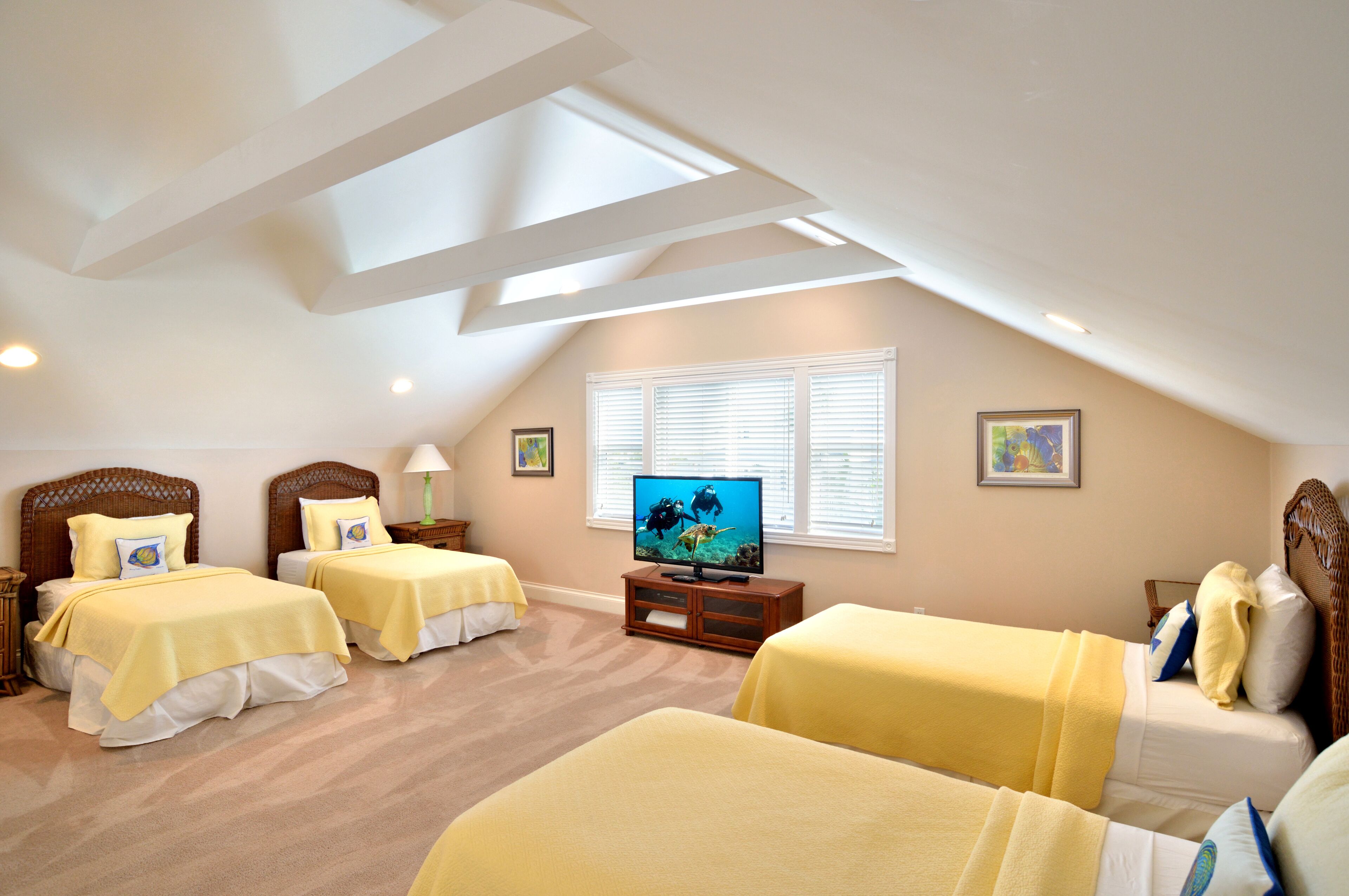 Ein Schlafzimmer mit zwei Betten, einem Fernseher und einem Fenster mit Jalousien.