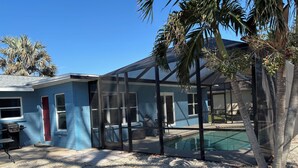 Una casa con piscina, patio cubierto y palmeras.