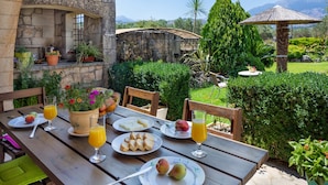 A wooden table set with plates of food, glasses of juice, and a potted plant. - Private 4-Bedroom villa, large pool, amazing gardens, relaxing family vacations (Chania)