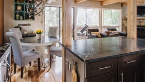 A modern kitchen with a large island, wooden flooring, and a stone backsplash.