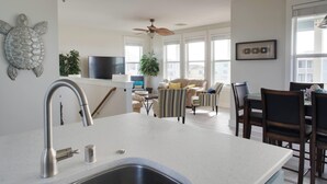 Une cuisine moderne dotée d’un évier encastré, d’un ventilateur de plafond et d’un coin repas avec des chaises et une table.