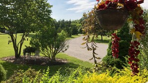 Une composition florale suspendue, agrémentée de feuilles séchées et de fleurs rouges, un arbre et une pelouse bien entretenue.