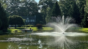 Une fontaine dans un parc, avec une maison en arrière-plan.