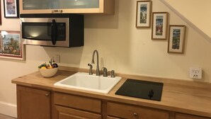 A kitchen with a sink, a microwave, and a stove. There are framed pictures on the wall. - A Cozy-kept Secret  Studio Located In The Heart Of 14/u St/logan Corridors (Washington)