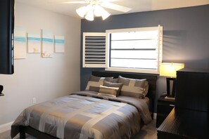 A bedroom with a bed, a window with blinds, a ceiling fan, and wall art. - Home away from Home? Paradise in the Sun? Why not call it both! HEATED Pool ! (Tarpon Springs)