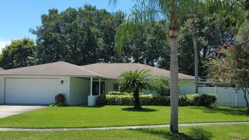 A single-story house with a garage, a well-maintained lawn, and a palm tree.