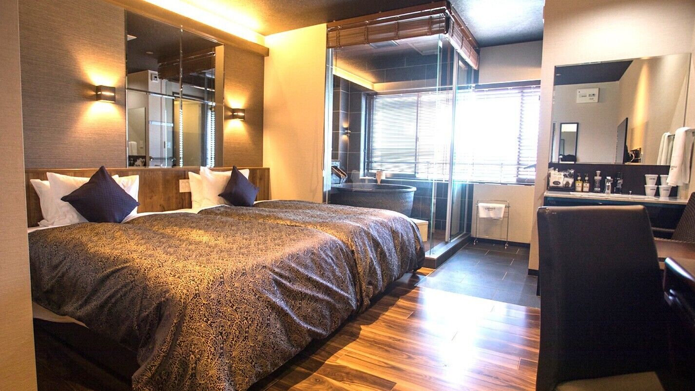 Habitació d'hotel amb un llit gran, un escriptori, una cadira, un bany i una vista per la finestra.