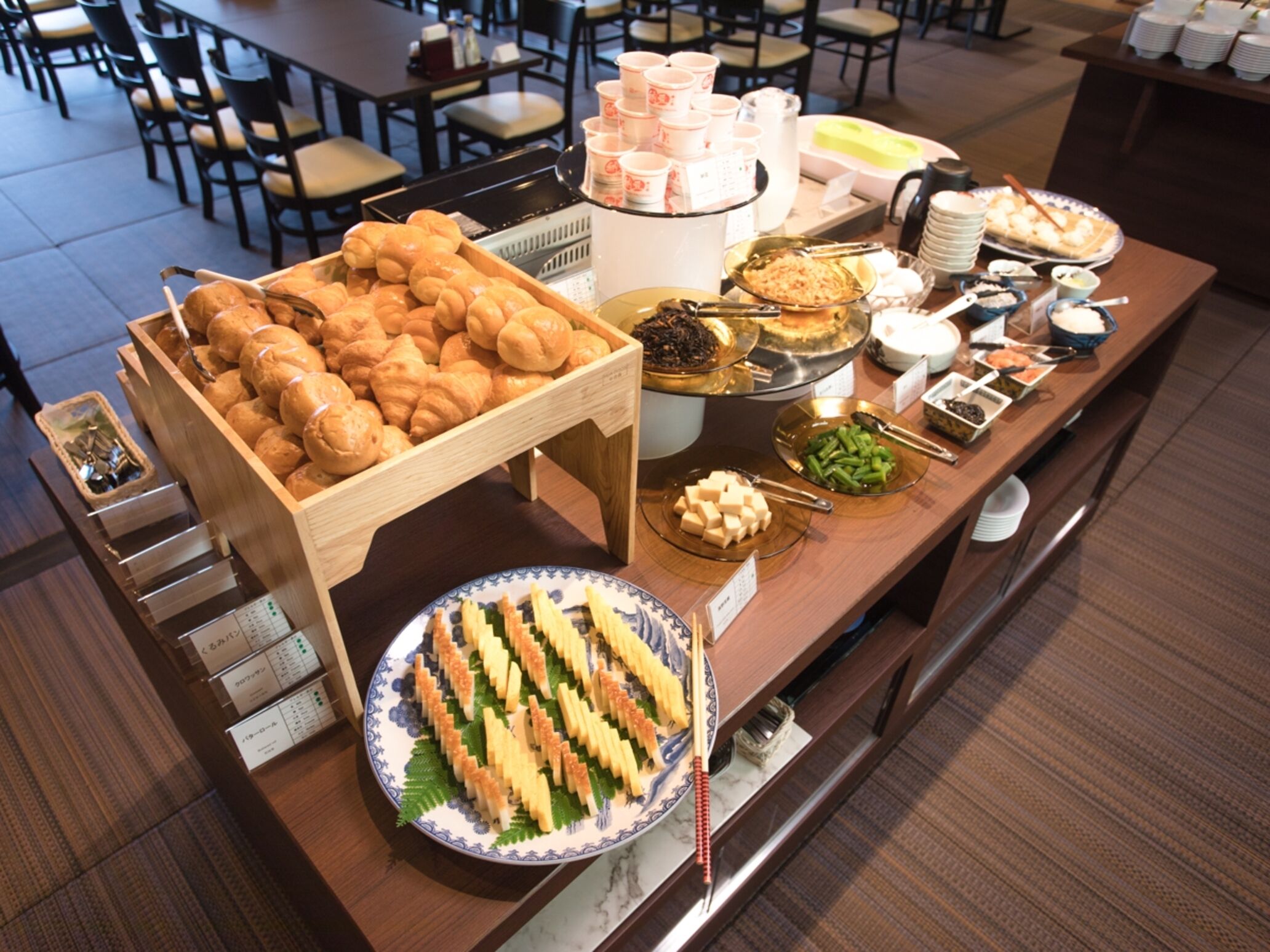 Buffet com diversos alimentos, incluindo pães, doces e saladas.