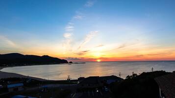 Une vue sur le coucher de soleil sur la côte, avec une plage et des immeubles résidentiels au premier plan.