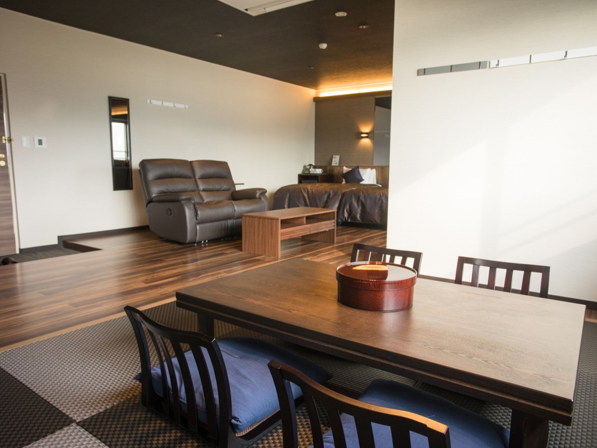 A modern living room with a wooden dining table, leather sofas, and a coffee table.