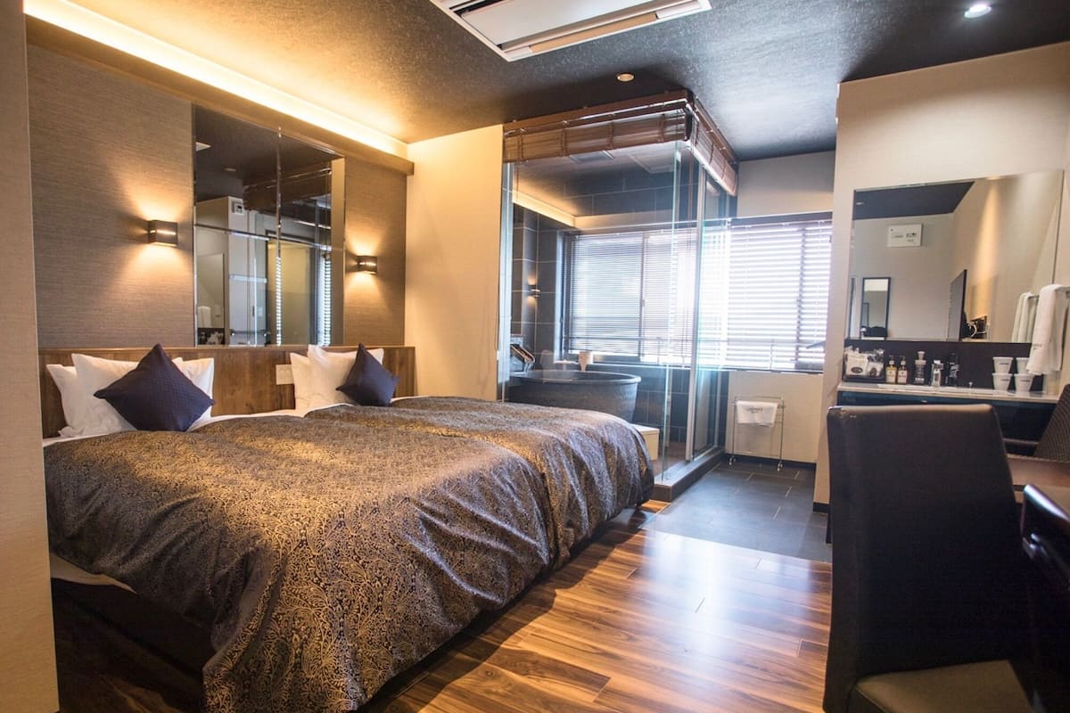 A modern hotel room with a large bed, a bathroom with a bathtub, and a seating area.