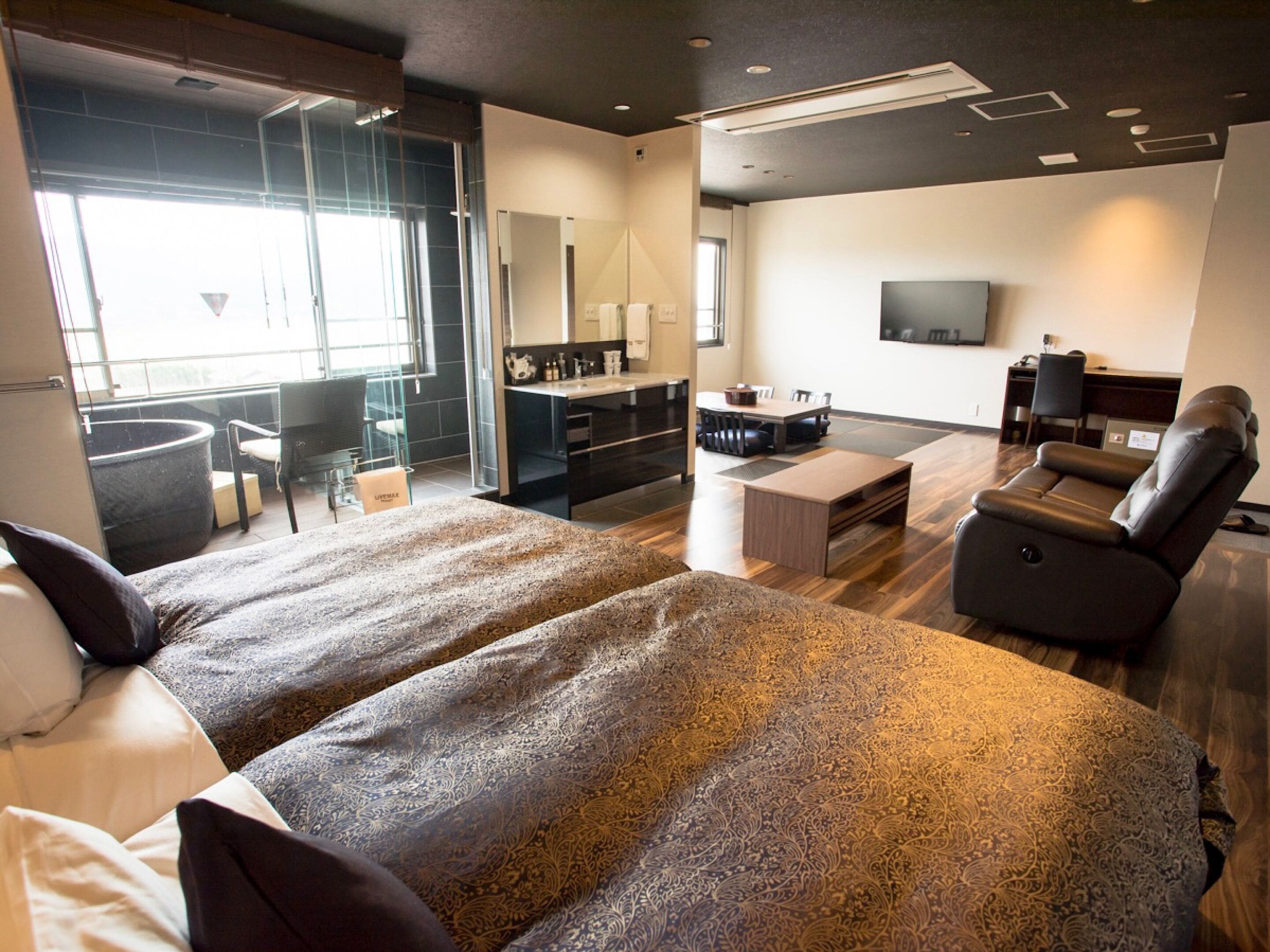 Een moderne hotelkamer met een groot bed, een bank, een televisie en een eethoek.
