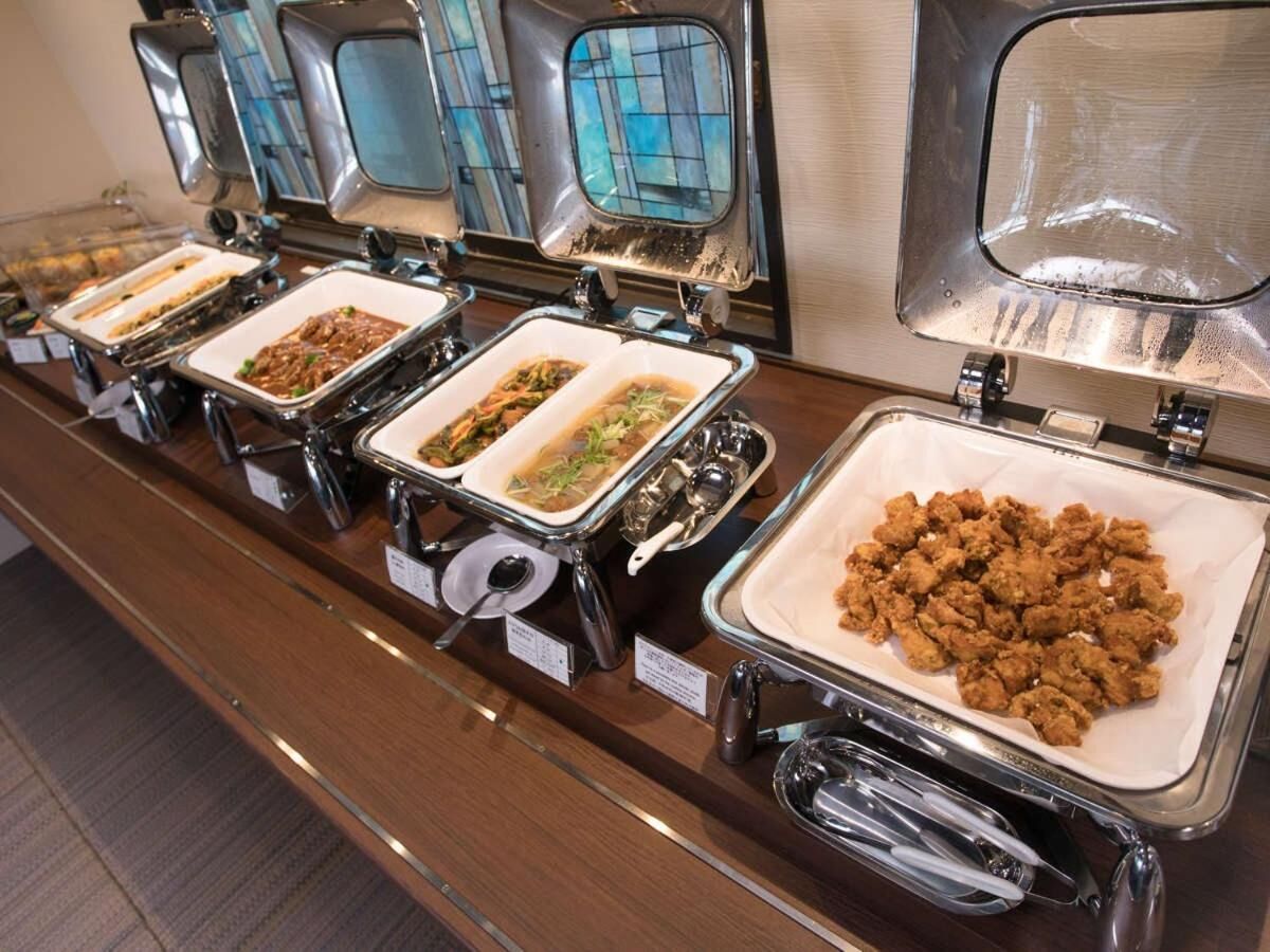 A buffet with various food options, including a tray of fried chicken, a dish with vegetables, and other assorted dishes.