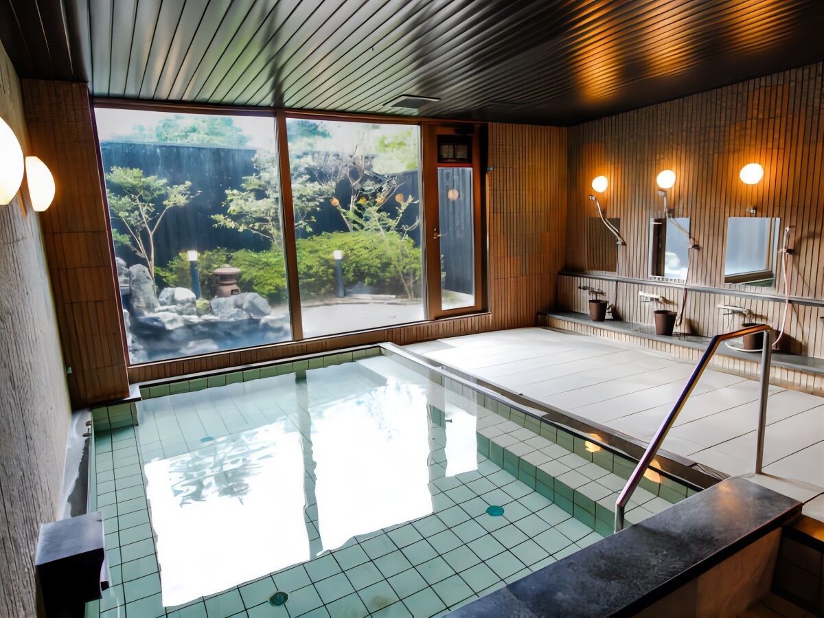 A traditional Japanese onsen with a clear view of a natural landscape through large windows.