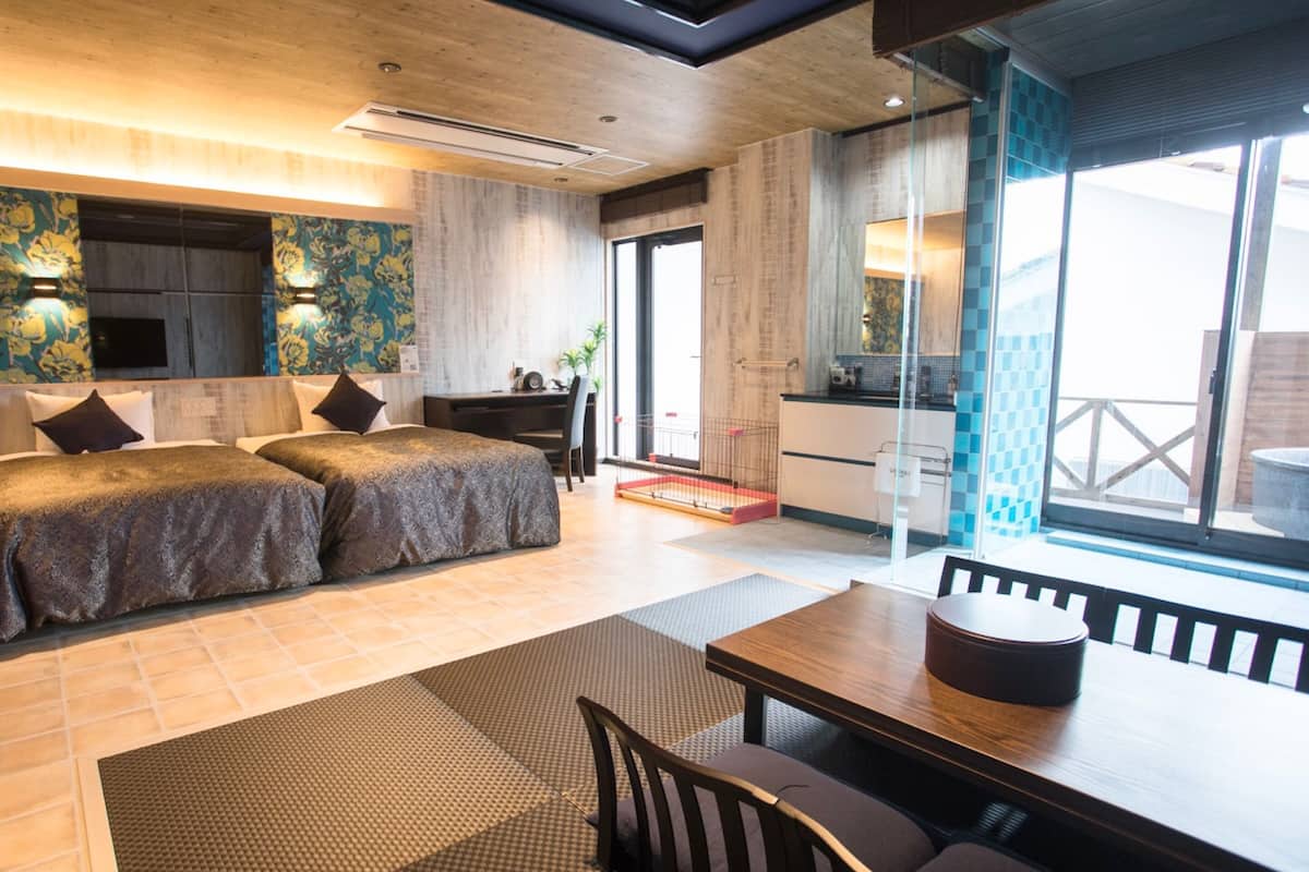A modern hotel room with a large bed, a desk, and a dining area.