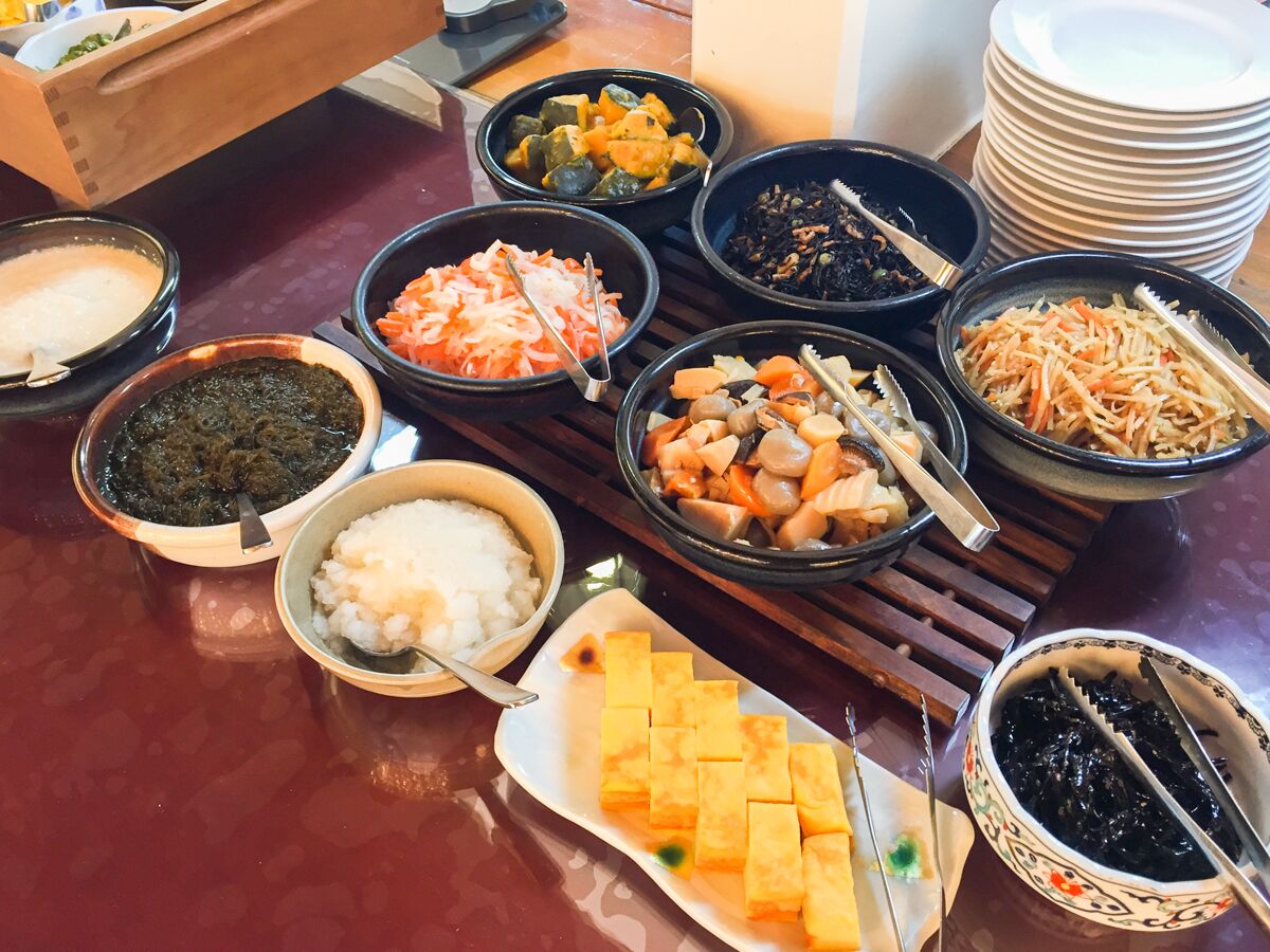 Una mesa con diversos platos, incluyendo tofu, verduras y arroz.
