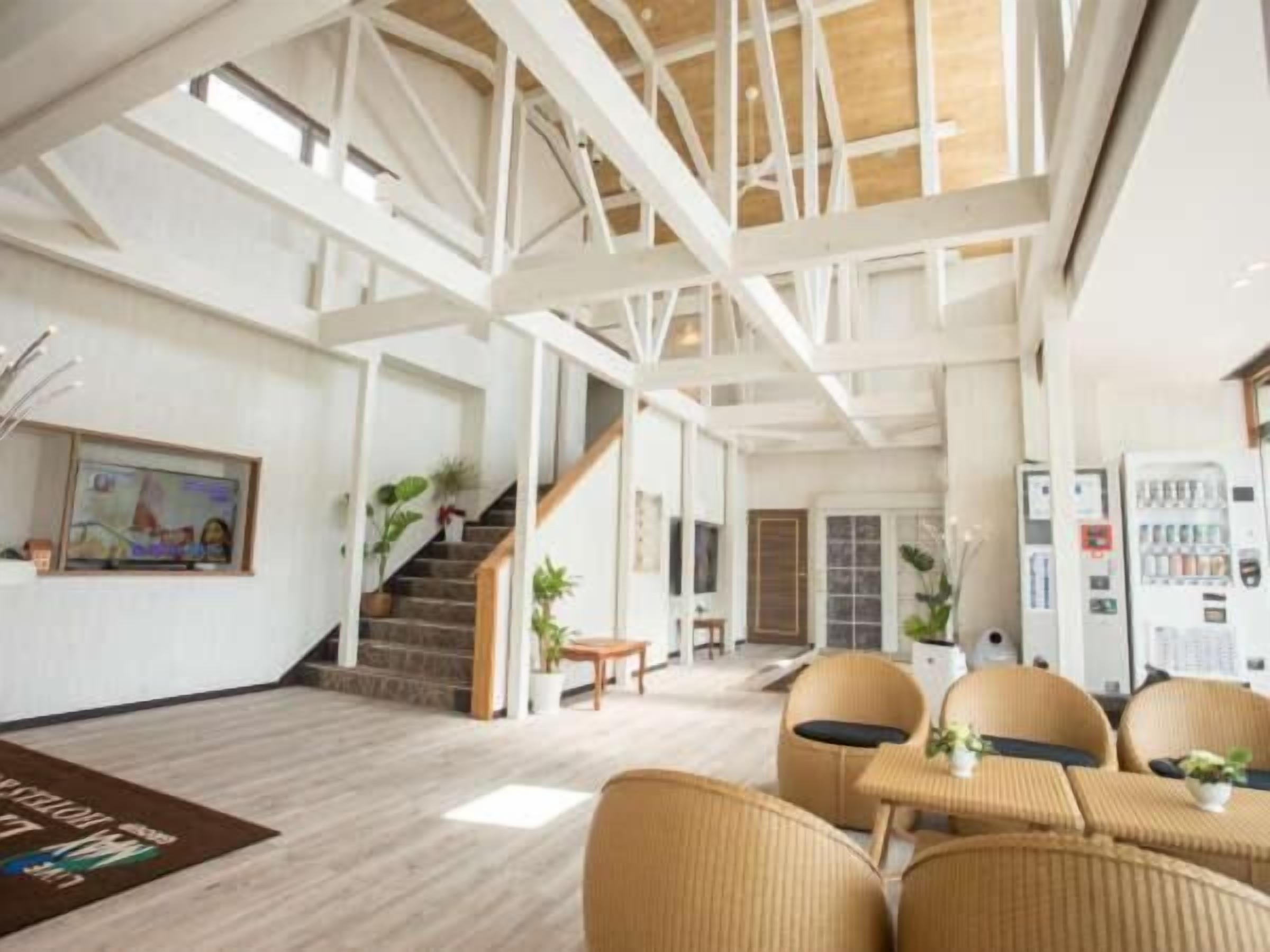 A spacious living area with high ceilings, a staircase, and wicker furniture.