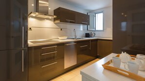 Una cocina moderna con electrodomésticos de acero inoxidable, un ventanal amplio y una bandeja con tazas blancas.