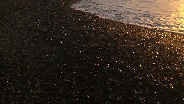 A beach with waves and a sunset.