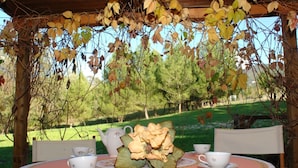 An outdoor table set with a floral tablecloth, a pitcher, cups, and a decorative centerpiece.