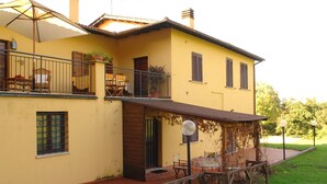 A yellow building with a balcony, a door, and a window.