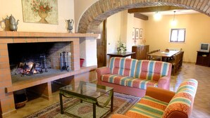 A cozy living room with a fireplace, a striped sofa, and a dining area with a table and chairs.