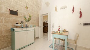 Une cuisine avec des meubles de couleur turquoise, une table à manger avec des chaises et une porte donnant sur une autre pièce.