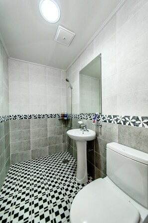 A bathroom with a toilet, sink, and shower. The floor has a black and white checkered pattern.