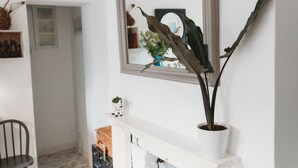 A white fireplace with a potted plant on the mantel.
