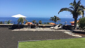A patio with a table and chairs, a white umbrella, and a view of the ocean. - Casa Tagoro, facing the Ocean.  (Tacoronte)