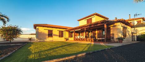 A two-story house with a patio, a lawn, and a clear sky.