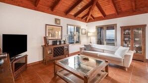 A living room with a wooden ceiling, a white sofa, a glass coffee table, and a television. - Casa Tagoro, facing the Ocean.  (Tacoronte)